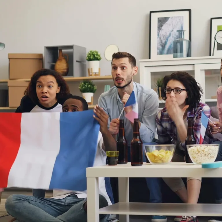 Groupe d’amis regardant un match de football en direct à la télévision, tenant un drapeau français, représentant l’expérience de streaming HD et 4K offerte par HexaCastIPTV