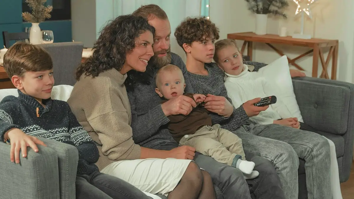 Famille souriante profitant d’un film sur grand écran avec un abonnement IPTV stable